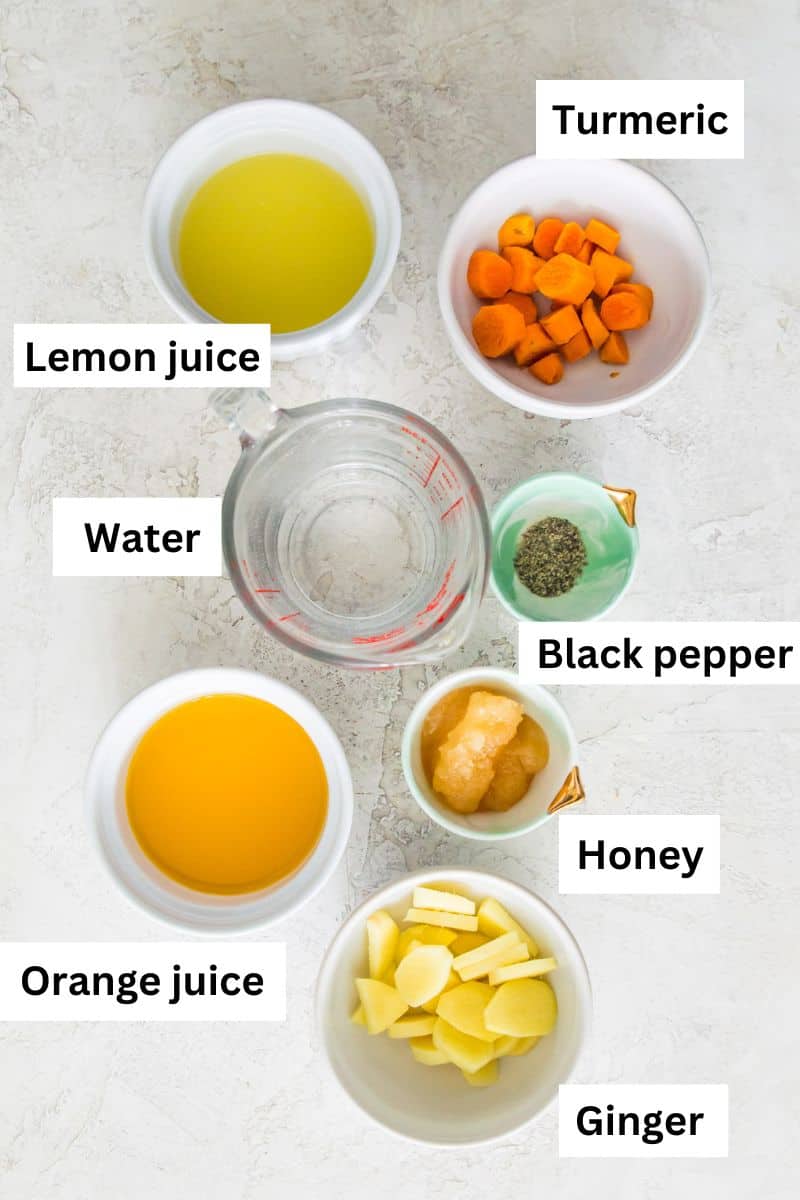 The ingredients needed to make ginger turmeric wellness shots separated into small bowls including water, orange juice, lemon juice, pieces of ginger, turmeric and honey.