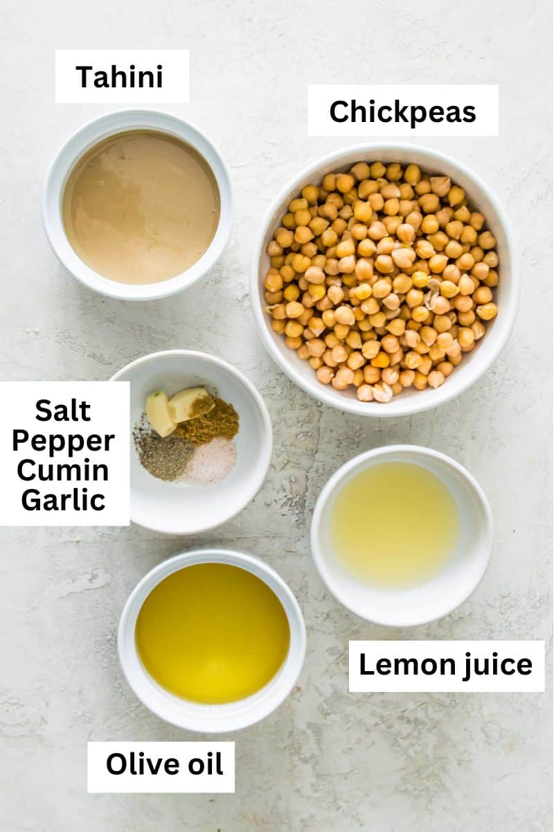 The ingredients needed to make a gluten free hummus separated into bowls including chickpeas, tahini, lemon juice, olive oil and spices.