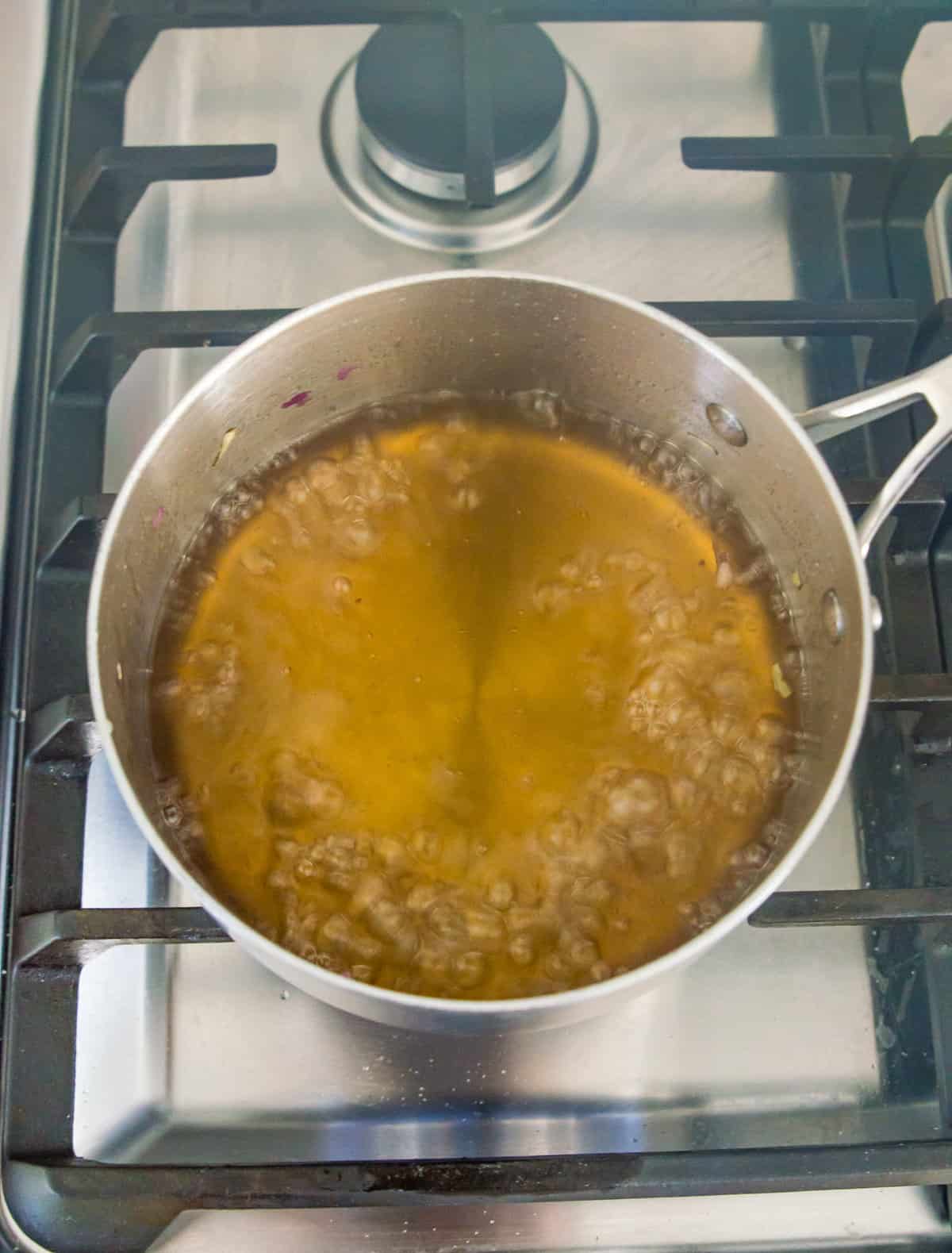 A pot filled with boiling sugar water on the stovetop.