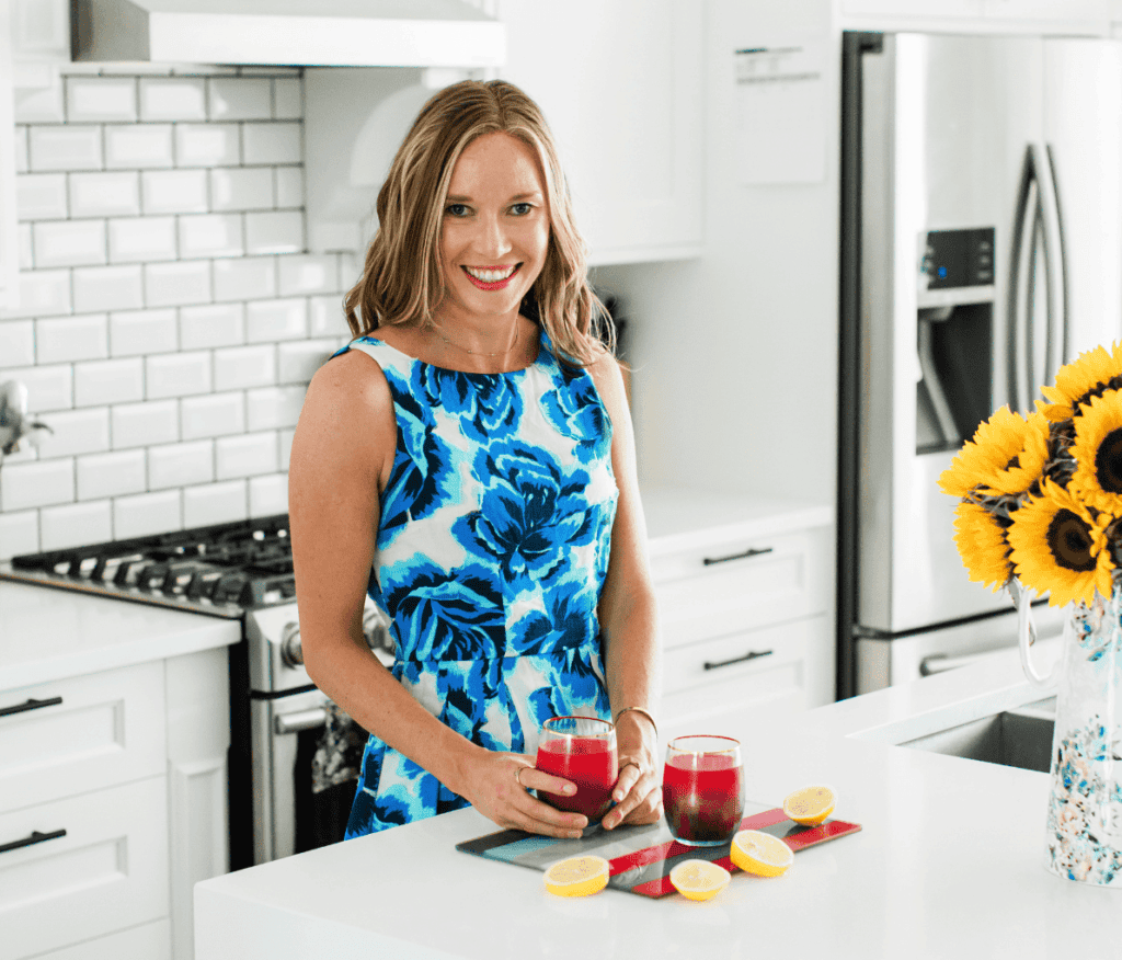 A photo of Dr. Erin Carter wearing a floral dress in her kitchen.