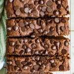 A loaf of double chocolate zucchini bread topped with chocolate chips cut into slices.