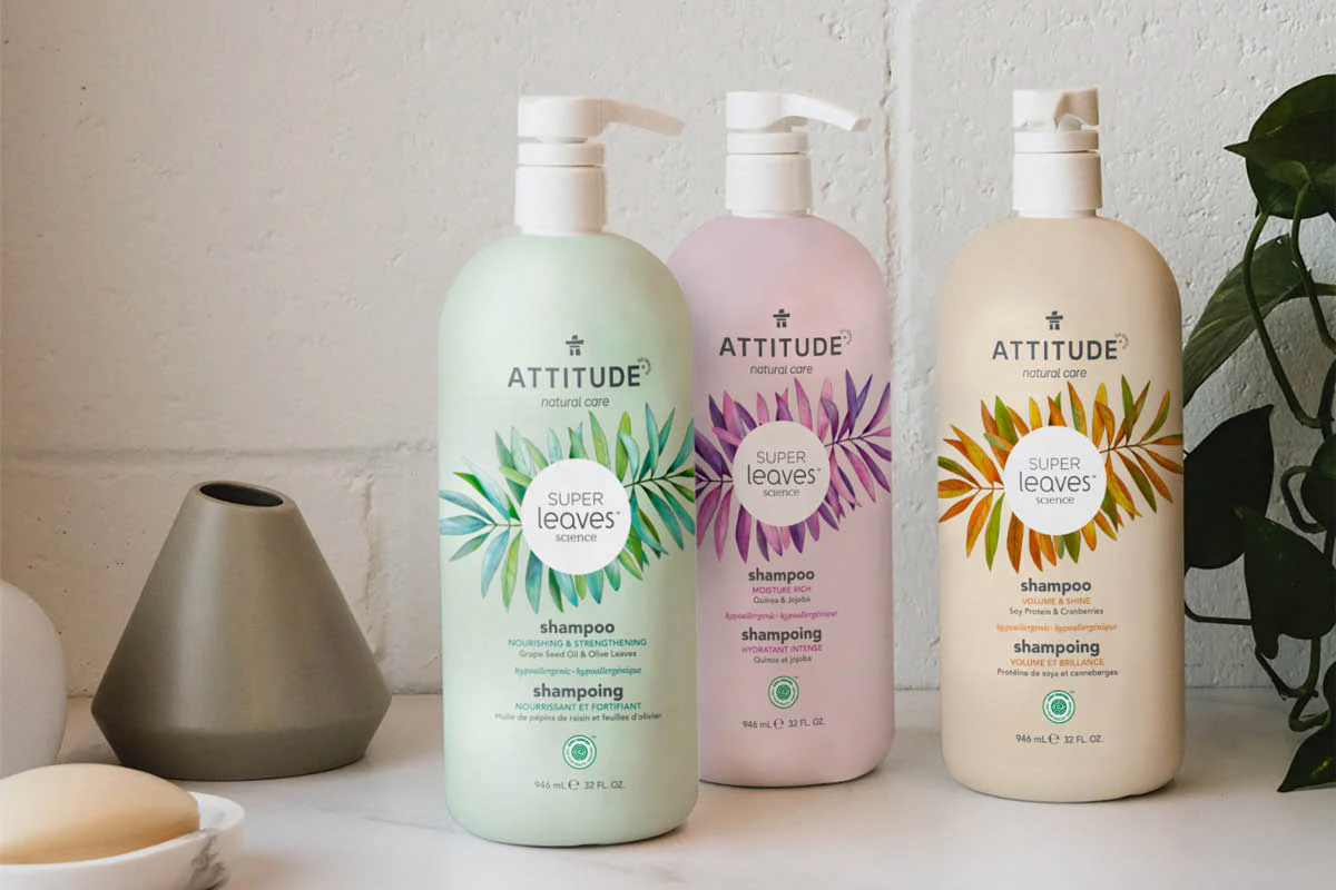 Three bottles of Attitude Living shampoo with a plant next to them.