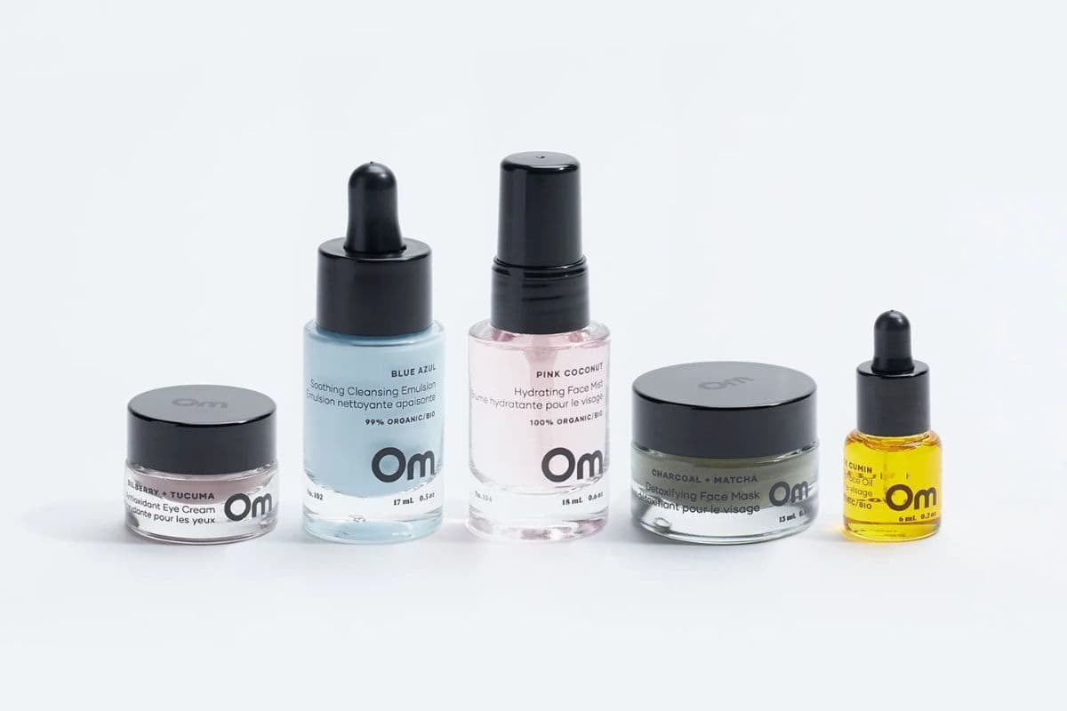 Five bottles of Om Organics skincare products lined up next to each other.