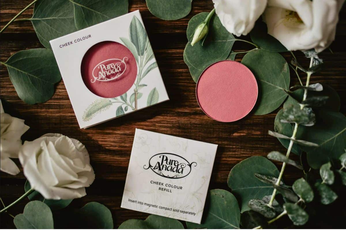 Three different powder blushes surrounded by white roses and green foliage.