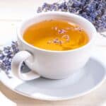 A mug of lavender tea with dried lavender flowers around it.